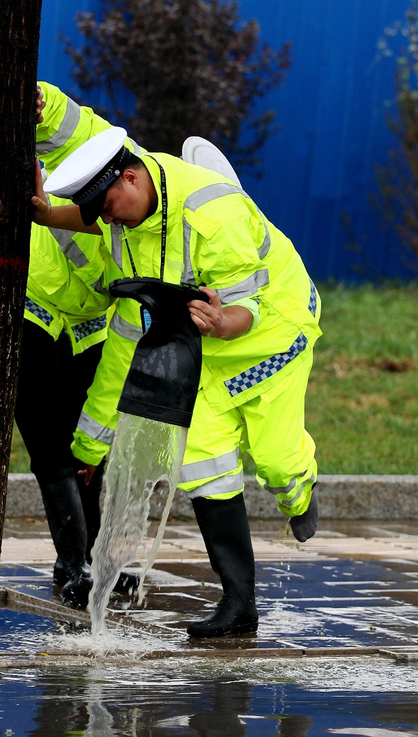 图为民警在路边倒掉雨靴中的积水继续战斗图为民警与工作人员清理积水